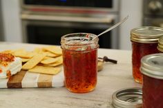 a table topped with jars filled with food next to crackers and cheesecakes