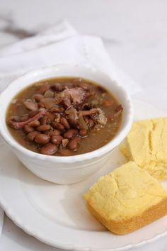 a white plate topped with a bowl of beans and bread