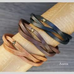 four different colored leather bracelets stacked on top of each other with gold stars in the middle