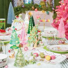 a table topped with plates and cups filled with desserts next to christmas tree decorations