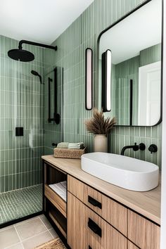 a bathroom with green tiled walls and flooring, including a large mirror over the sink