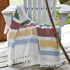 a white rocking chair with a striped blanket on it and a wooden stick in the foreground