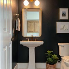 a bathroom with a sink, toilet and mirror in it's corner next to a door