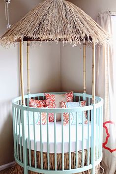 a baby crib with a straw roof and pillows on it's sides, in front of a white wall