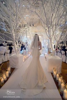 the bride is walking down the aisle in her wedding dress, with candles on the floor