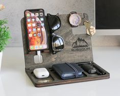 an iphone, sunglasses, and other items are arranged in a holder on a desk