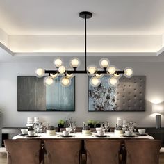 a dining room table and chairs with two paintings on the wall above it, along with an artful chandelier