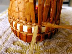 a close up of a woven basket on a table cloth with two wooden chopsticks sticking out of it