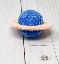 a blue ball with an orange ring around it on a white wooden surface and the words, what is your creation?