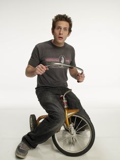 a man sitting on top of a bike holding a knife in his right hand and looking surprised at the camera