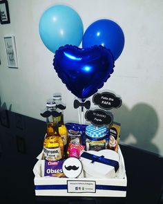 a box with some blue balloons and other items in it that are on a table