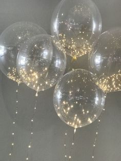 five clear balloons with lights hanging from them