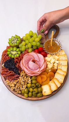 a platter filled with meats, cheeses and grapes