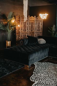 a living room with a black couch and leopard rug