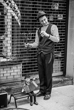 a man standing next to a little boy on a bench in front of a building