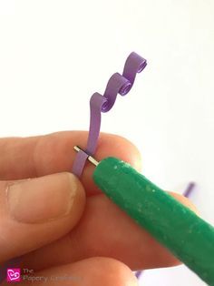 someone is holding a tiny green and purple toothpick with the word love spelled on it