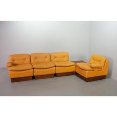 an orange leather sectional sofa with matching footstool and ottoman in front of a white wall