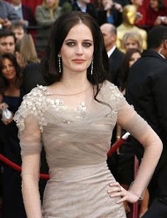 a woman in a dress standing on a red carpet with her hands on her hips