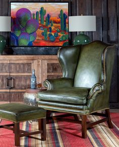 a green leather chair and ottoman in front of a painting