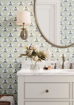 a bathroom vanity with a mirror above it and flowers in the vase on the counter