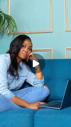 a woman sitting on a blue couch with her laptop computer in front of her face