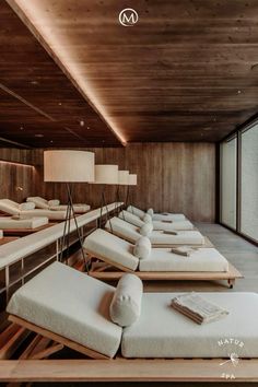 a long row of white couches in a room with wooden walls and flooring