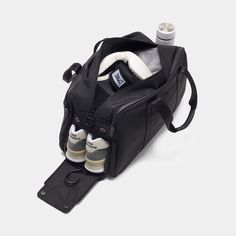 an open black duffel bag with baby bottles and diapers in the bottom compartment