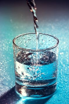 water being poured into a glass with ice cubes in it