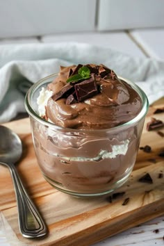 a glass bowl filled with chocolate pudding on top of a wooden cutting board