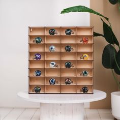 a display case filled with football helmets on top of a white table next to a potted plant