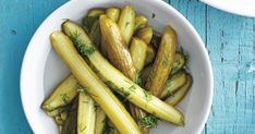 a white bowl filled with cucumbers on top of a blue table