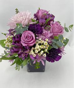 a vase filled with purple flowers and greenery