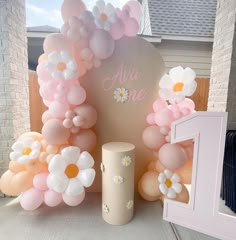 an arrangement of balloons and flowers on display in front of a sign that says age one