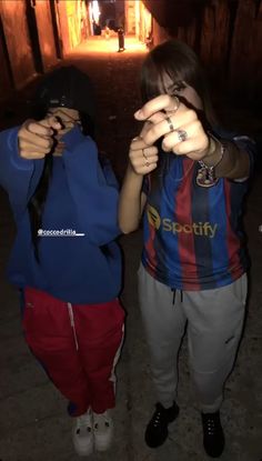 two girls are standing in the dark with their hands together