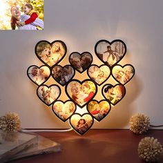 a lighted heart shaped photo frame with multiple photos on the front and side, sitting on a table next to flowers