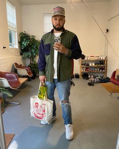 a man holding two bags in his hands while walking through a room with chairs and other furniture