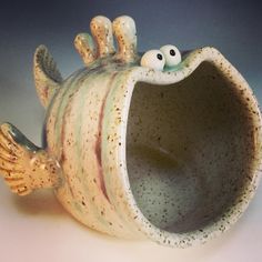 a ceramic fish shaped vase with eyes on it's head and legs sticking out