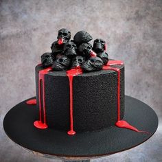 a black cake with red icing and skulls on top