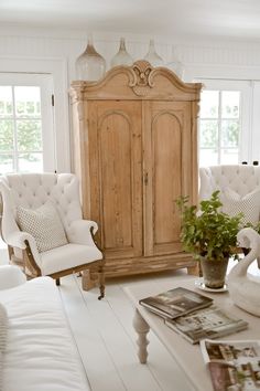 a living room filled with furniture and a tall wooden cabinet next to a white couch