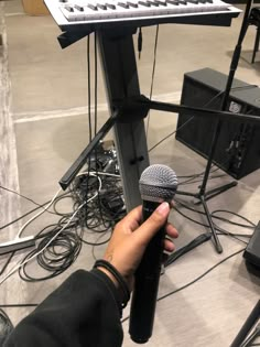 a person holding a microphone in front of a keyboard and other electronic equipment on the floor