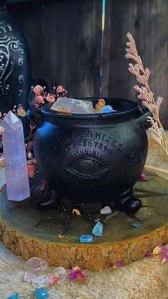 a black caulder sitting on top of a wooden table next to a vase