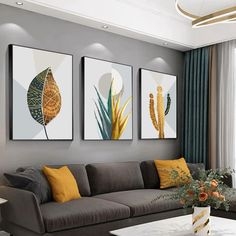 three paintings hang on the wall above a couch in a living room with grey walls