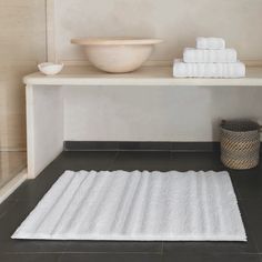 a white bathroom rug on the floor next to a bowl