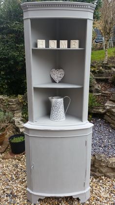 the corner cabinet is painted gray and has a white vase on top, with letters that spell home above it