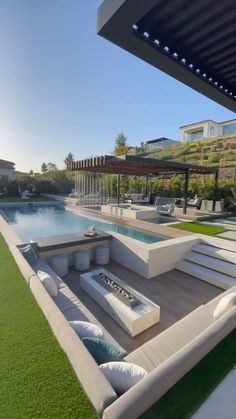 an outdoor living area with couches and tables next to a swimming pool in the background