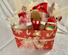 a red christmas basket filled with stuffed animals and candy canes on top of a white table cloth