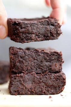 chocolate brownies are stacked on top of each other and being held by someone's hand