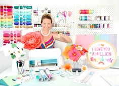 a woman sitting in front of a sewing machine with lots of crafting supplies on the table