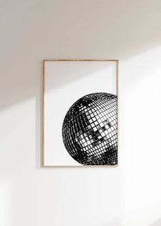 a black and white photo hanging on the wall next to a wooden frame with an image of a disco ball