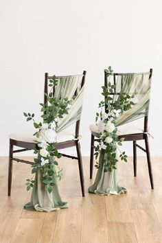 two chairs decorated with flowers and greenery